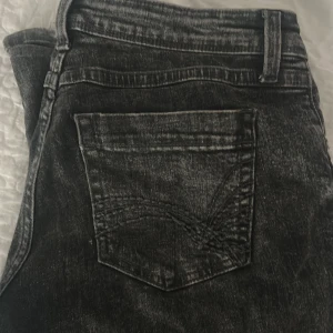 Svarta jeansbyxor från H&M Divided - Säljer ett par svarta jeansbyxor från H&M Divided med tvättad look. De är sköna och lite baggy, lite slitna där nere men man ser inte det så tydligt🤍