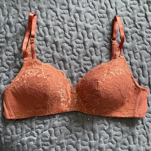 Rostfärgad BH - Säljer en rostfärgad bh med vacker spets och justerbara axelband. Perfekt för dig som vill ha något både snyggt och bekvämt.