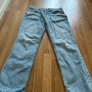 Ljusblå jeansbyxor baggy  - Säljer ett par klassiska ljusblå jeansbyxor med rak passform. Byxorna har fem fickor, bälteshällor och stängs med dragkedja och knapp. Perfekta för en avslappnad stil och passar till det mesta.