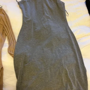 Grå tight klänning med smala axelband - Säljer en enkel och stilren grå klänning med smala axelband. Klänningen är tight och har en rak, kroppsnära passform. Perfekt för dig som gillar minimalistisk stil.