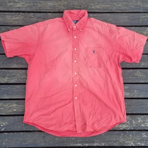Rosa skjorta från Polo Ralph Lauren - Rosa ralph lauren skjorta  Hej! Jag säljer en riktigt snygg kortärmad ralph lauren skjorta i storlek XL men som också kan passa L. Skicket är 9/10 ⭐️ med inga fläckar eller defekter. Väldigt fin och perfekt plagg inför sommaren som är nära 🌞!   Orginalpris: 1500kr Mitt pris: 299kr Går med på bud så buda gärna! Skriv också om ni har några frågor.