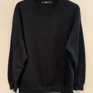 Svart sweatshirt från FB Sister - En klassisk svart sweatshirt från FB Sister med rund halsringning och långa ärmar. Tröjan har en avslappnad passform och ribbade muddar vid ärmslut och nederkant. Perfekt basplagg till garderoben.