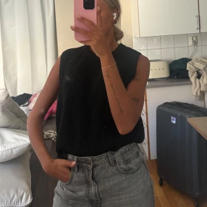 Svart stickad väst från Lindex - Säljer en svart, ribbstickad väst från Lindex i storlek S. Västen har en rund halsringning och är ärmlös, perfekt att styla över en skjorta eller t-shirt. 