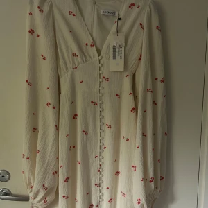 Vit blommig Positano-klänning Adoore - Supersöt vit Positano-klänning från Adoore med små röda blommor, helt ny strl xs/34! Nypris 1695kr! Hade en likadan i strl xxs men den passade inte o denna passade inte heller! De är den långa modellen 