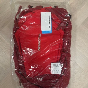 Röd ryggsäck Salomon Trailblazer 30L - Säljer en röd Salomon Trailblazer 30L ryggsäck med sportig design och flera smarta fack. Perfekt för till vandring, ny med oöppnad förpackning 🤍ORGINALPRIS 1100kr