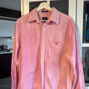 Rosa oxfordskjorta från Gant M - Snygg rosa oxfordskjorta från Gant i storlek M. Skjortan har klassisk krage, bröstficka med broderad Gant-logga och knäppning framtill. Tillverkad i bomull och har lång ärm. Perfekt för en clean och stilren look. Perfekt till midsommar