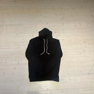 Pier One Hoodie med vit snörning - En stilren svart hoodie med huva och vita snören. Tröjan har en klassisk känguruficka framtill och långa ärmar. Perfekt för en bekväm men snygg outfit och passar till det mesta. 