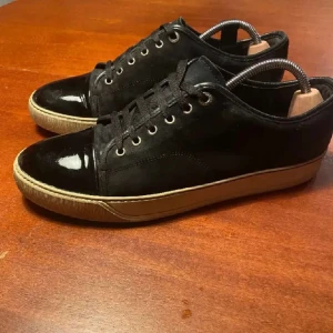 Svarta sneakers från Lanvin i mocka och lack - Tja! Säljer dessa feta svarta lanvins i storlek 44 och innersulan är runt 30 cm. Skorna är i okej skick och har inga defekter utan mockan är lite smutsig och sulorna lite gula. De har lite slitningar. Skick, 7/10. Det ingår ingen box eller dustbag, bara skorna. Kontakta gärna för frågor eller för extra bilder!