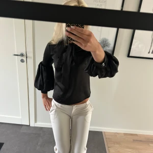 Svart blus med puffärmar Daisy Grace - Supersnygg svart blus från Daisy Grace med stora puffärmar och knytband i halsen. Storlek xs men skulle säga att om du har s så funkar den också. Bra skick.