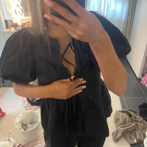 Svart blus med puffärmar och snörning - Säljer en svart blus med voluminösa puffärmar och snygg snörning framtill vid halsen. 