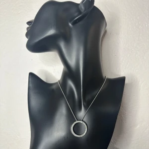 :Vintagehalsband från farmors smyckesskrin - glittrande cirkelhänge – Unisex, 60/70-tal, möjligen sterling  silver - Vintagehalsband från farmors smyckesskrin, troligen från 60-/70-talet. Cirkelhänge med infattade kristaller i silvrig metall. Kedjan är 38 cm + 7 cm förlängning. En otydlig stämpel sitter vid låset – typiskt för äldre silverkedjor, men ej testat. Säljs som oädel metall med möjlighet till silvervärde. Fint skick med lätt patina. Prutning accepteras ej, men jag erbjuder rabatt vid köp av flera saker. Jag rensar smyckesskrin & garderob – kika gärna på mina andra annonser!  ⸻ 