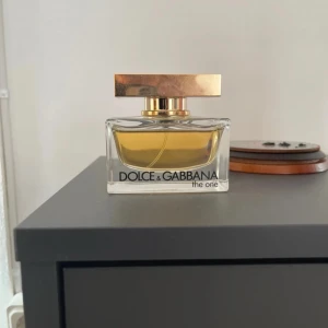 Dolce & Gabbana The One EdP 50 ml - Dolce & Gabbana The One Eau de Parfum i 50 ml flaska. Parfymen kommer i en elegant, rektangulär glasflaska med guldigt lock och bär en varm, gyllene vätska. En klassisk och lyxig doft som sticker ut i badrumshyllan.