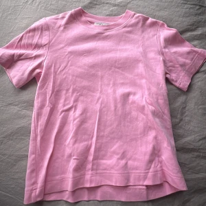 Rosa t-shirt från COS - Enkel och stilren rosa t-shirt från COS i mjuk bomull. T-shirten har klassisk rund halsringning och korta ärma.