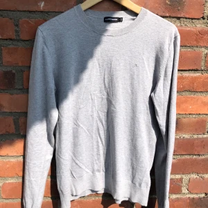 Ljusgrå j.lindberg tröja - Snygg ljusgrå tröja från J.Lindeberg i bomull. Enkel och stilren design med rund halsringning och diskret logga på bröstet. Storlek S men har krympt lite i tvätten så sitter ungefär som xs!