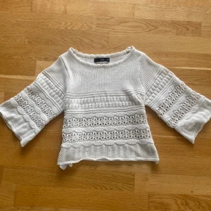 Vit stickad croppad tröja från Mango - Superfin vit stickad tröja från Mango med croppad passform och trekvartsärmar. Tröjan har snygga virkade detaljer och breda ärmar som ger en chill vibe. Perfekt till jeans eller kjol på sommaren när du vill ha en söt och trendig look.