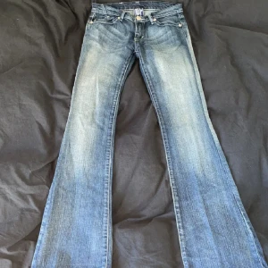Victoria Beckham jeans - Snygga blå jeans med bootcut. Jeansen har slitningar framtill och coola broderade kronmotiv på bakfickorna. Klassisk femficksmodell i jeansmaterial med normal passform och låg midja.