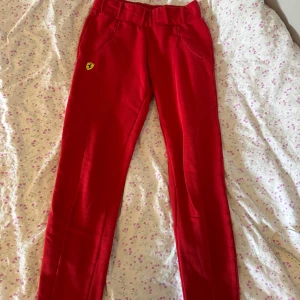 Puma x Ferrari röda byxor  - Jättefina byxor med Ferrari och Puma logo, passande form. Äkta. Säljer pga de är alldeles för små för mig. Midjan går att justera. Mjukisbyxor. Midja 70cm, längd 94cm.
