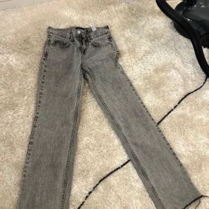 Grå raka jeans - Snygga grå jeans med raka ben och klassisk femficksdesign. Jeansen har en ljusgrå tvätt och normal passform, perfekta till sneakers eller boots. Stängs med knapp och dragkedja.