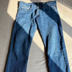 Replay Grover straight fit jeans blå - Snygga blå jeans från Replay, modell Grover med straight fit. Klassisk femficksdesign, normal passform och mellanblå tvätt. Tillverkade i mjukt jeanstyg med subtila slitningar och kontrastsömmar. Perfekta för en avslappnad och stilren look.
