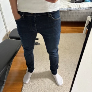 Slim fit mörkblå jeansbyxor 32/32 - Snygga mörkblå jeansbyxor i slim fit-modell med klassiska fickor och kontrastsömmar. Modellen heter Lou Slim och har en modern, smal passform som sitter tajt men ändå bekvämt. Perfekta för dig som gillar stilrena och enkla jeans.
