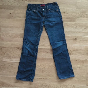 Levi's 557 blå jeans flare fit - Klassiska blå Levi's 557 "Eve" jeans med vida ben nertill låg midja och snygga kontrastsömmar. Modellen har fem fickor, normal passform och ikonisk läderpatch bak. Jeansen är tillverkade i slitstarkt denim och har en tidlös look som funkar till allt.