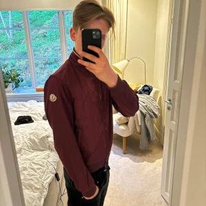 Röd moncler windbreaker  - Säljer denna vin röda moncler windbreakern.                                              Storlek: 2 i moncler vilket motsvarar S. Killen på bilden är 180.                                                                                             Mycket fint skick men använd men inget som syns✅.                                                                                                        Rabatt om man följer ✅