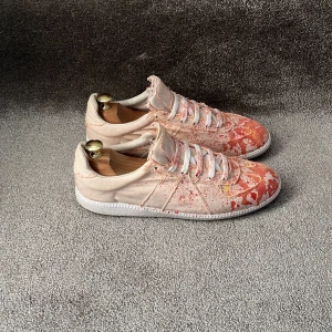 Maison Margiela skor - Hej! Säljer dessa riktigt snygga och unika skor från Maison Margiela i canvas material med  ”paint splatter”! 🔥riktigt fet design med tillgjorda råa slitna kanter, färgstänk och en ”replica” av GATS som tyska armén hade på 70 talet! Perfekta för dig som vill sticka ut från mängden! Tydligt och väl använda (se alla bilder)! Nypris är ~8000kr! Storlek 44 men jag upplever att skorna skulle passa dig bättre som bär 43! 100% äkta vilket jag står för! Box, snören och skorna medföljer vid köp! Mvh DC 🔹