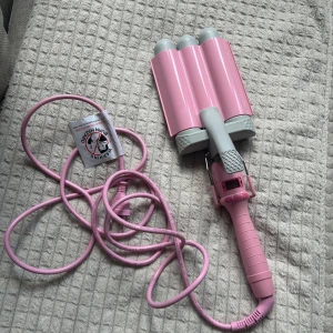 Mermaid waver  - Säljer en rosa Mermaid Waver från med tre cylindrar som är 32mm och har digital display. Perfekt för att skapa snygga beach waves. Tången har grå detaljer och lång sladd, och är tillverkad i plast och metall. Enkel att använda med smidiga knappar på handtaget. Kan värmas upp till 180 grader