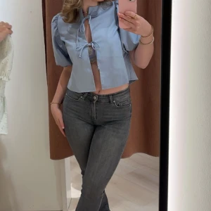 Ljusblå blus med puffärm och knyt från Gina  - Supersöt ljusblå blus med korta puffärmar och två knyt framtill. Blusen är croppad och har en luftig passform som ger en trendig vibe. Tröjan är i storlek xs och är ifrån Gina Tricot💕