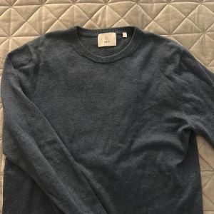 Mörkblå stickad tröja från Bläck - En stilren mörkblå stickad tröja från Bläck i storlek S. Tröjan har rund halsringning, långa ärmar och är tillverkad i ett mjukt material som passar perfekt för kyligare dagar. Enkel och clean design som funkar till det mesta.