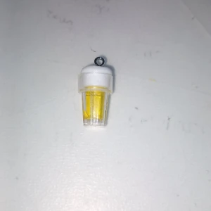 Gul milkshake-hänge till halsband - Supergulligt hänge som ser ut som en liten milkshake med gul dryck och vit topp. Perfekt att sätta på ett halsband eller armband för en lekfull och unik stil. Gjord i plast med metallögla för enkel fastsättning.