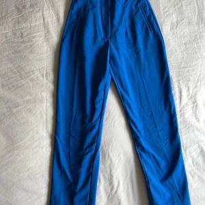 Zara marinblå byxor med raka ben - Snygga marinblått  byxa med raka ben och diskreta fickor framtill. Byxorna har en klassisk passform och är perfekta för dig som vill sticka ut med färg. Materialet känns mjukt och följsamt, vilket gör dem bekväma hela dagen.Mycket fin skick.