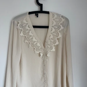 Snygg blus från vero Moda  - Jätte snygg blus i luftigt material. Den är beige och har knappar man kan knäppa. Har en form av spets längst med tröjan. Från vero Moda i storlek s.