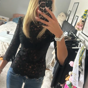 Svart spetsblus med snörning -  Svart blus i spets med trekvartsärm och snörning i ryggen. 