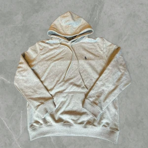 Grå hoodie från Polo Ralph Lauren  - Säljer en stilren grå hoodie från Polo Ralph Lauren med klassisk huva och dragsko. Storleken är slim fitt xl vilket är ungefär M