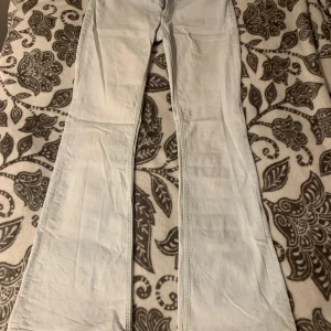 Ljusblå flare jeans från H&M - Säljer ett par ljusblå flare jeans från H&M med låg midja och justerbar midja. Jeansen har klassisk femficksdesign och är tillverkade i mjukt bomullstyg. Perfekta för dig som gillar retrovibbar och vill ha en snygg siluett.