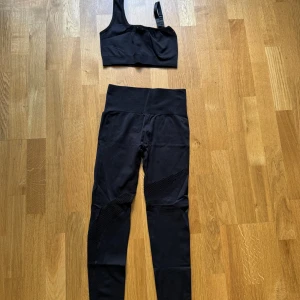 Svarta seamless tights med hög midja och matchande topp - Svarta seamless tights  med hög midja och diskreta mesh-detaljer på benen & matchande topp. Tillverkade i stretchigt material som sitter skönt och följsamt. Perfekta för träning eller chill. Säljes utan märke.