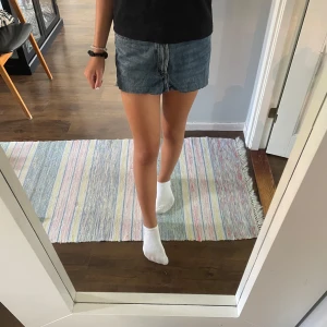 Blå jeanskjol med fransig kant - Snygg kort jeanskjol i blå denim med rå, fransig nederkant och klassiska fickor fram och bak. Kjolen har normal passform och stängs med dragkedja och knapp..
