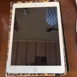 iPad  - Det finns ingen bok på bilderna, utan en iPad (sjätte generationen) med 32 GB lagring. Ingen information om någon boktitel, författare eller innehåll kan utläsas från bilderna.