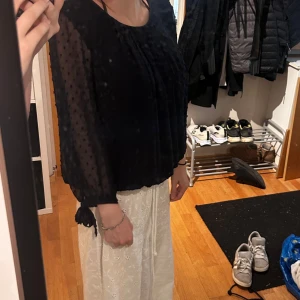 Svart prickig blus med knytärmar - Säljer en marinblå blus med transparent tyg och prickigt mönster. Blusen har långa ärmar med snygga knytband vid ärmsluten och en loose passform. Perfekt för dig som gillar detaljer och vill ha något som sticker ut lite extra. Knappt använd, storlek M. 