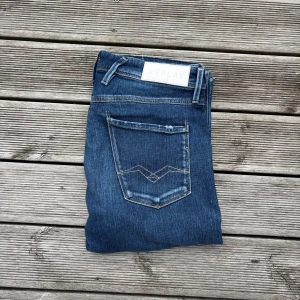 Blå Replay jeans slim fit Anbass - Säljer ett par klassiska blå jeans från Replay i slim fit. Jeansen har snygg tvätt med ljusare partier, fem fickor och detaljerade bakfickor. Tillverkade av återvunnen denim för en schysstare stil. Perfekta till sneakers eller boots. Kom gärna med frågor!🙌