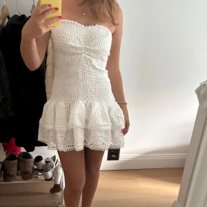 Vit klänning - Supersöt vit klänning med axelbandslös design och volangkant. Helt ny med prislappen kvar!