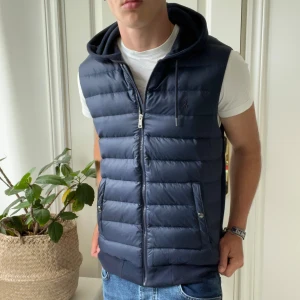Väst ralph Lauren mörkblå  - 10/10 skick, Skönnn Ralph Lauren vest med zip, Luva, fickor med lyxiga knappar. Har fler bilder så bara skriv! Modellen bär M och är 180,75 kg. Skulle inte rekommendera för någon under 175 eller över 190! 🙏