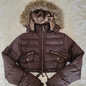 2000s jacka med pälsluva - Fantastisk höstjacka från Gotha Love 🍂  Croppad modell med snörning nertill och fakepäls på luvan 💕 Sann till storlek (M), kan anpassas för att passa mindre med knytbandet i midjan. Även två fickor med dekorativa knappar som stängs med dragkedja och gulligt rutigt foder!  Det enda riktiga tecknet på användning är en liten missfärgning på ena fickans dragkedja, se sista bilden! I övrigt är jackan i mycket gott skick och redo för nya äventyr ❤️  Pris är självklart förhandlingsbart 😊