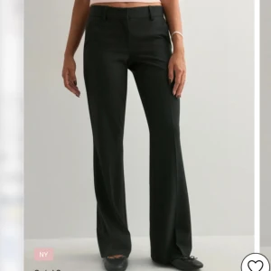 Svarta bootcut kostymbyxor - Snygga svarta kostymbyxor med bootcut-silhuett och midwaist. Byxorna har hällor för bälte, diskreta fickor bak och klassisk stängning fram. Perfekta för en clean och stilren look. Materialet är slätt och känns dressat. Byxorna är från Nelly och är slutsålda i storlek 32.