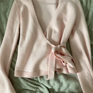 Ljusrosa omlottkofta  - Supersöt ljusrosa omlottkofta från SHEIN i mjuk stickad kvalitet. Koftan har långa ärmar, ribbade muddar och knytband i midjan för en snygg passform. Perfekt för lager-på-lager och ger en chill men ändå feminin vibe.