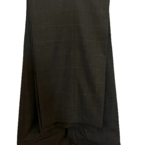 Svartgrå rutig kostym från SIR Regular Fit - Stilren svartgrå kostym från SIR i regular fit med diskret rutigt mönster. Kavajen har klassisk krage, två knappar och fickor med lock. Materialet är en mix av ull och polyester med lite elastan för extra komfort. Perfekt för dig som vill ha en snygg och modern look.