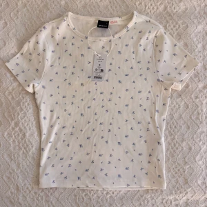 Vit blommig t-shirt från Gina Tricot - Supersöt vit t-shirt från Gina Tricot med små blå blommor över hela. Super skönt o helt ny
