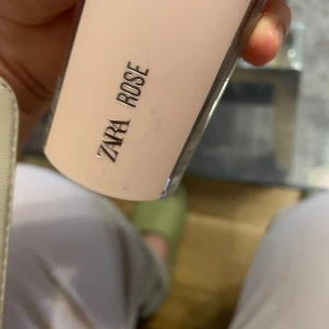 ZARA Rose parfym rosa flaska - ZARA Rose parfym i en stilren, rektangulär flaska med ljusrosa plastlock och detaljer. Flaskan är genomskinlig nedtill och visar parfymens innehåll. Doften är blommig och feminin, perfekt för dig som gillar rosiga toner.