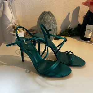 Klackar - Snygga gröna klackar från Zara med smala remmar och hög klack. Skorna har en öppen tå och elegant design som ger en trendig vibe. Perfekta för dig som vill sticka ut med färg och stil. Materialet känns mjukt och lyxigt.
